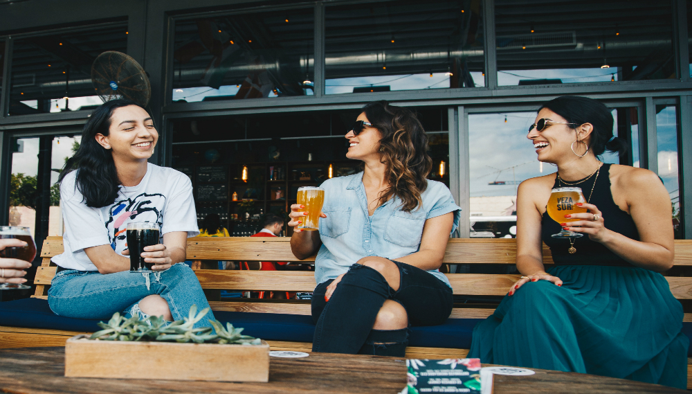 three women laughing while having a glass of beer