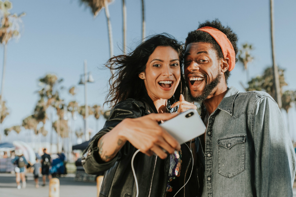 Man and woman smiling and taking a selfie on a beautiful day outside